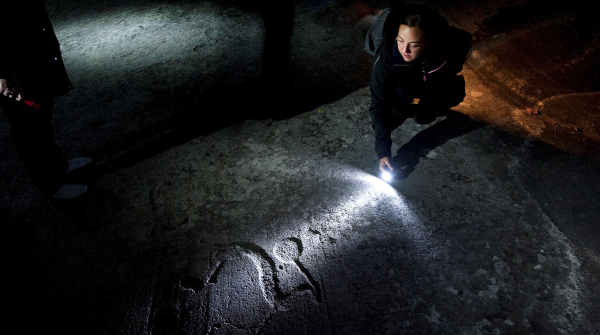 woman with flashlight and unpainted carving.