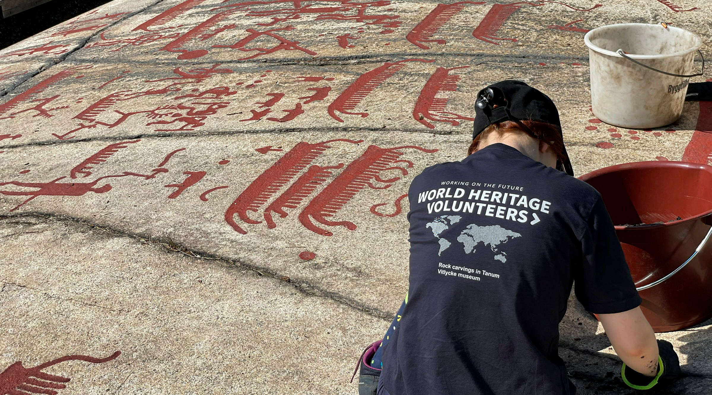 Eine Frau füllt Felszeichnungen mit roter Farbe aus