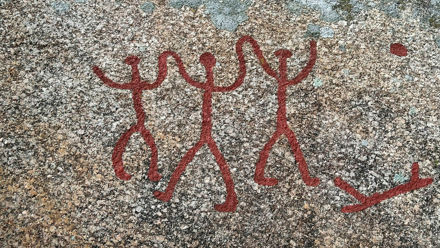 tre hällristningsfigurer håller händerna
