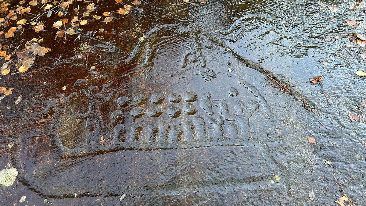 unpainted rock carving with boat and figures sumersauling.