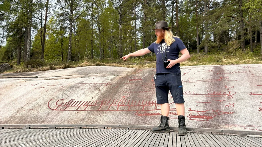 en man pekar på hällristning av stort skepp