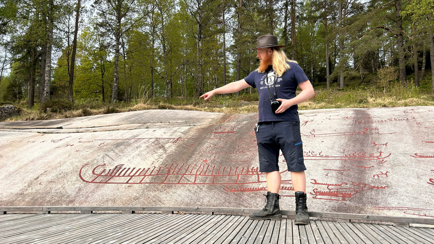 en man pekar på hällristning av stort skepp