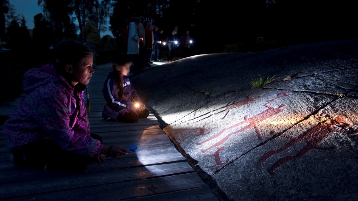 Children looking at the Fossum carving using flashlights.